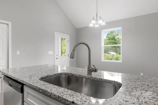 a kitchen with a granite countertop sink a window and refrigerator