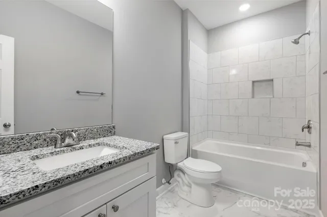 a bathroom with a granite countertop toilet a sink and a bathtub