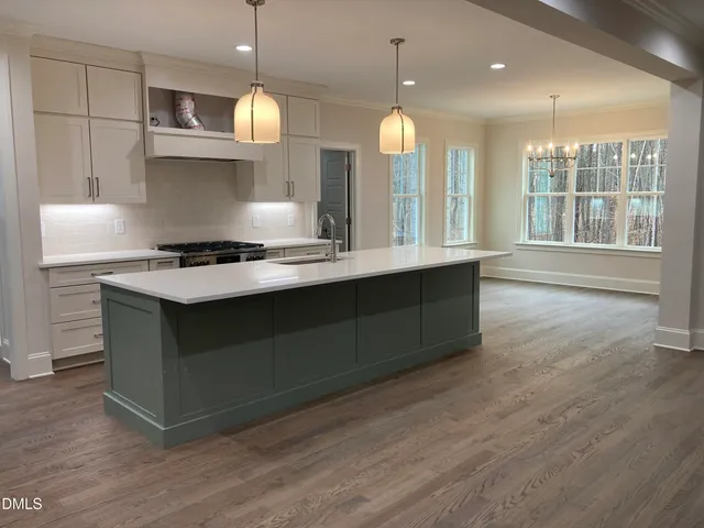 a kitchen with kitchen island granite countertop a stove a sink a window and wooden floors