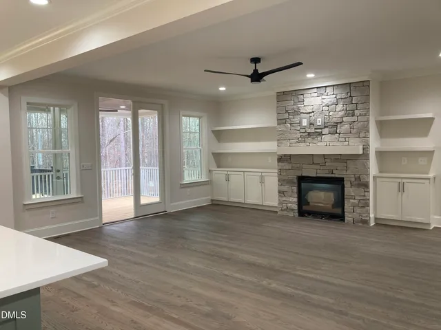 a view of an empty room with wooden floor fireplace and a window