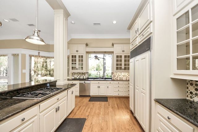 a large kitchen with granite countertop a stove refrigerator and cabinets