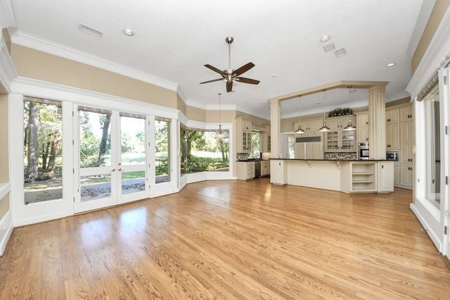 a view of a kitchen with kitchen island wooden floors and stainless steel appliances