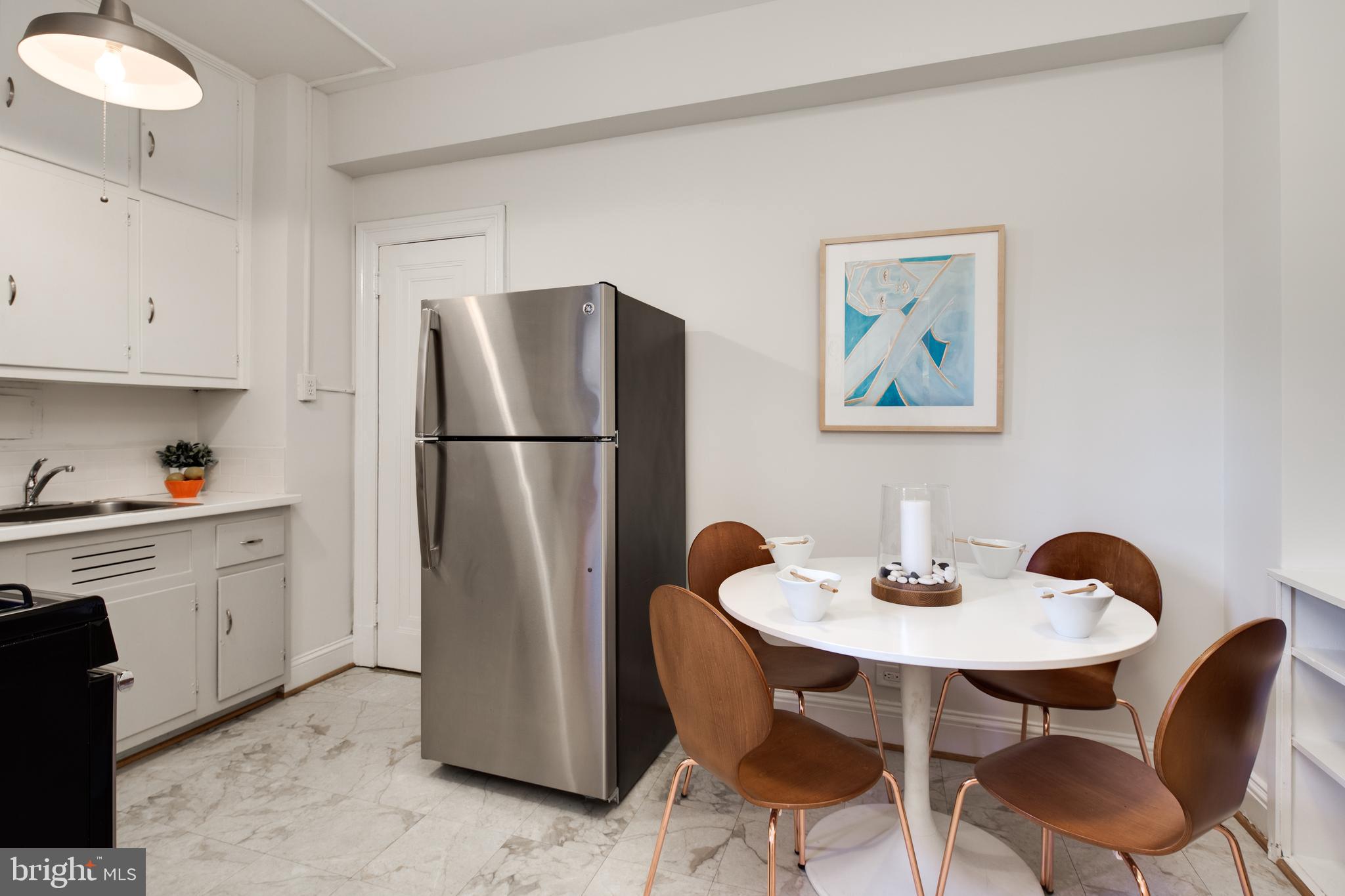 2707 Adams Mill Road Northwest, Unit 303 Washington, DC 20009 - Photo 14 of 30 a kitchen with stainless steel appliances a dining table and chairs