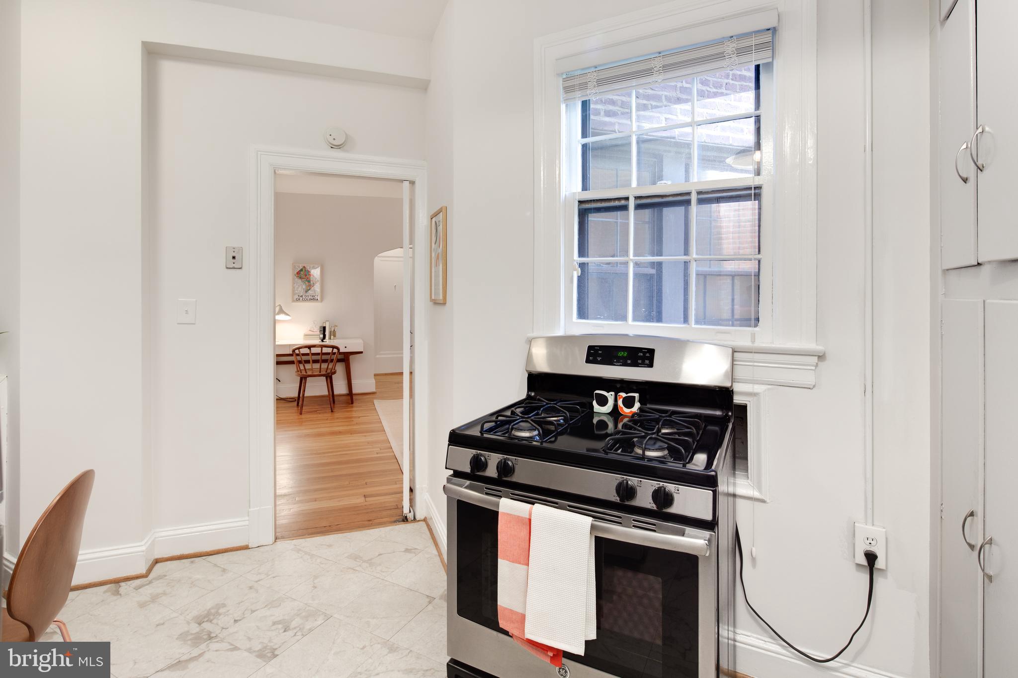 2707 Adams Mill Road Northwest, Unit 303 Washington, DC 20009 - Photo 15 of 30 a kitchen with stainless steel appliances granite countertop a stove and a view of living room