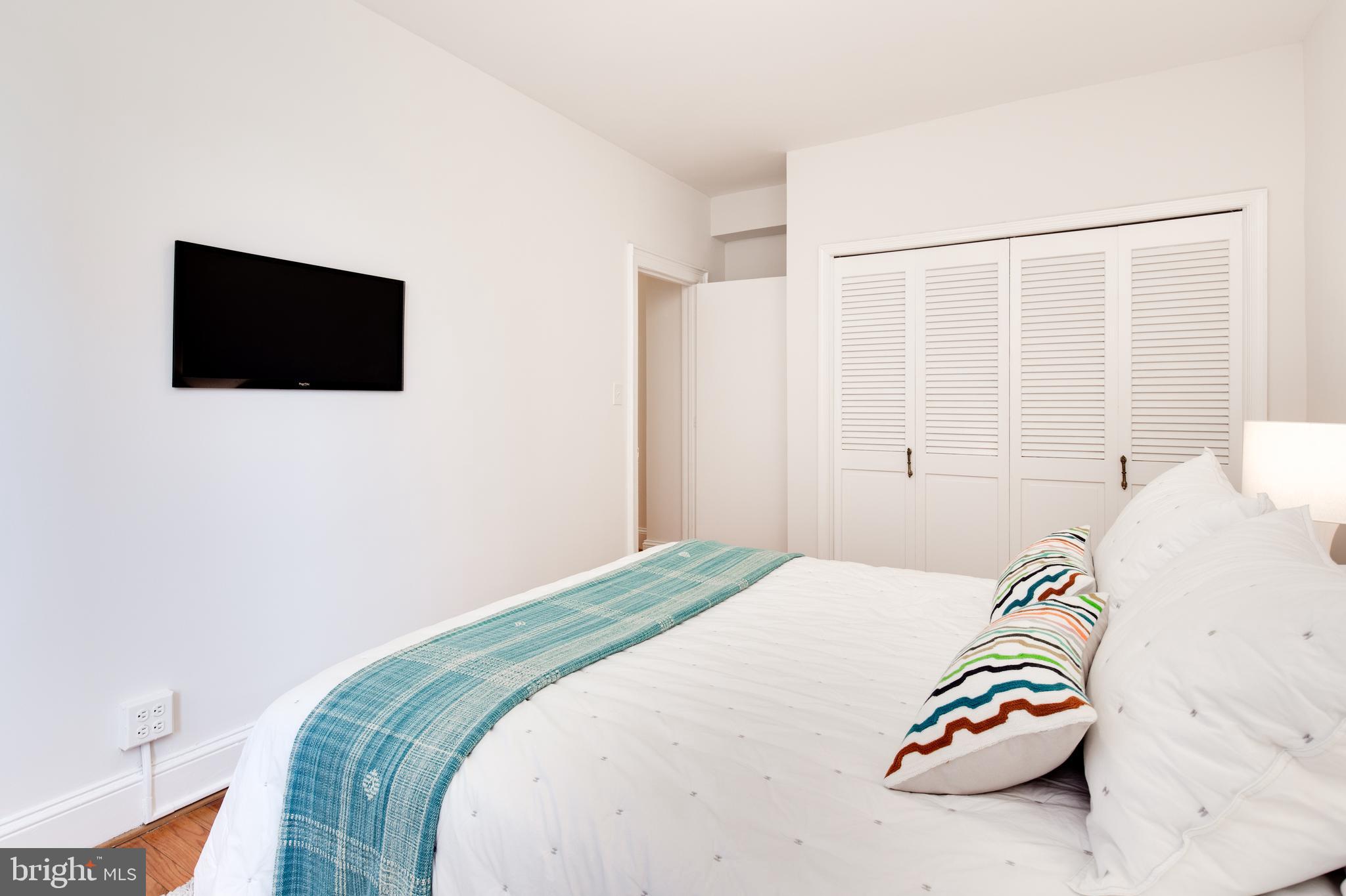 2707 Adams Mill Road Northwest, Unit 303 Washington, DC 20009 - Photo 23 of 30 a bedroom with a bed and a tv