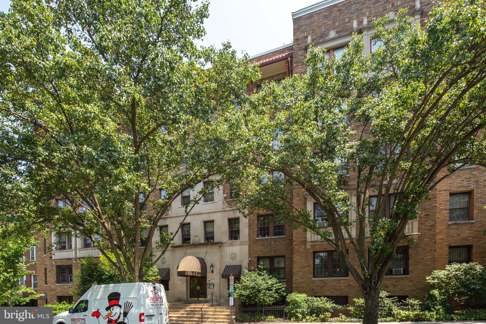 2707 Adams Mill Road Northwest, Unit 303 Washington, DC 20009 - Photo 29 of 30 a front view of a building with large trees and plants