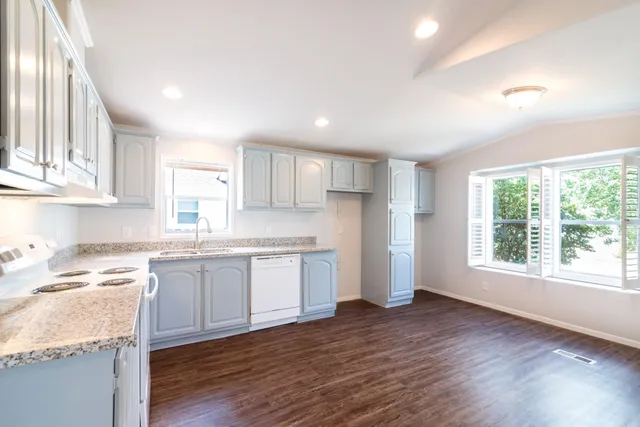 a kitchen with granite countertop white cabinets and wooden floor