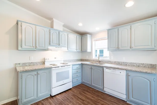 a kitchen with granite countertop stainless steel appliances white cabinets sink and dishwasher with wooden floor
