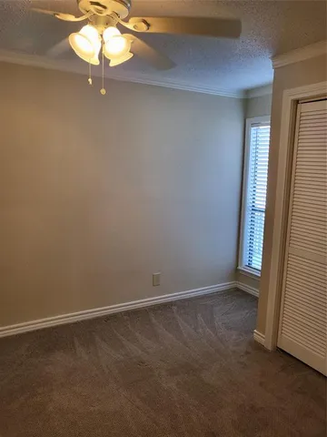 an empty room with a chandelier fan and window
