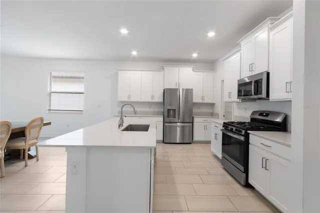 a kitchen with stainless steel appliances granite countertop a refrigerator a stove a sink a dining table and chairs