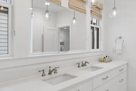 a bathroom with double vanity sinks a vanity a lamp and a mirror