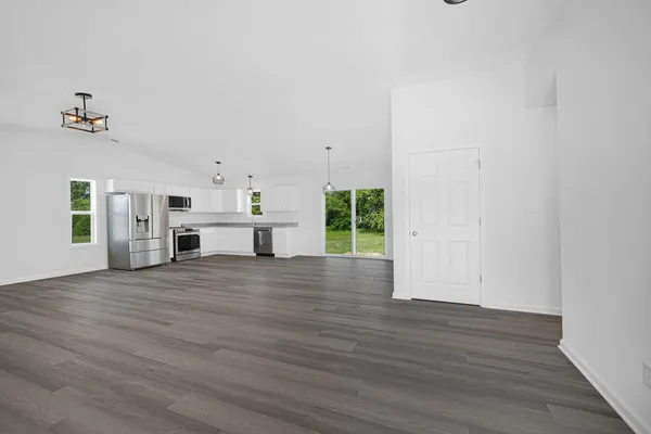 a view of an empty room with a window and wooden floor