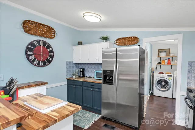 a kitchen with stainless steel appliances granite countertop a refrigerator a stove a sink dishwasher and white cabinets with wooden floor