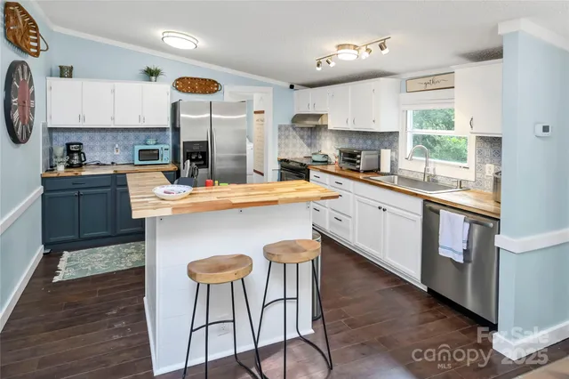 a kitchen with stainless steel appliances granite countertop a stove top oven a dining table and chairs with wooden floor