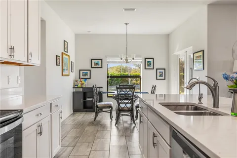 a kitchen with a sink a stove a refrigerator and white cabinets with wooden floor
