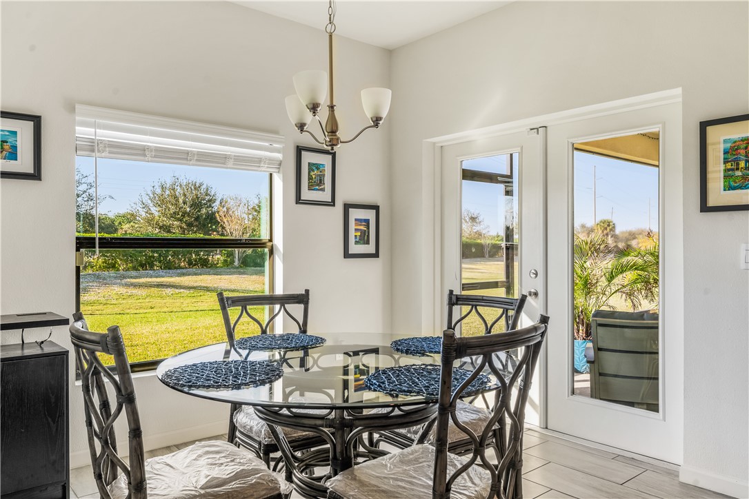 5760 1st Road Vero Beach, FL 32968 - Photo 16 of 36 a dining room with furniture a floor to ceiling window and wooden floor