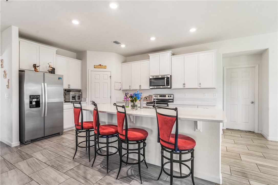 5760 1st Road Vero Beach, FL 32968 - Photo 3 of 36 a kitchen with stainless steel appliances kitchen island granite countertop a dining table chairs refrigerator and sink