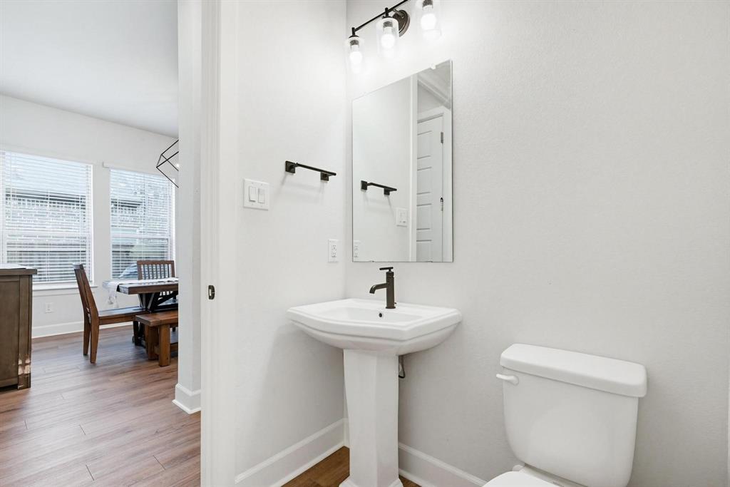 9341 Loggerhead Way Fort Worth, TX 76118 - Photo 19 of 35 Pedestal sink with a matte black faucet, wall-mounted mirror, and vanity lighting fixture