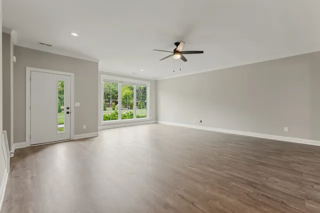 a view of an empty room with a window and wooden floor