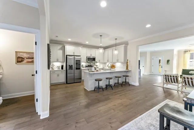 a kitchen with stainless steel appliances granite countertop a sink a stove top oven a refrigerator and dishwasher with wooden floor