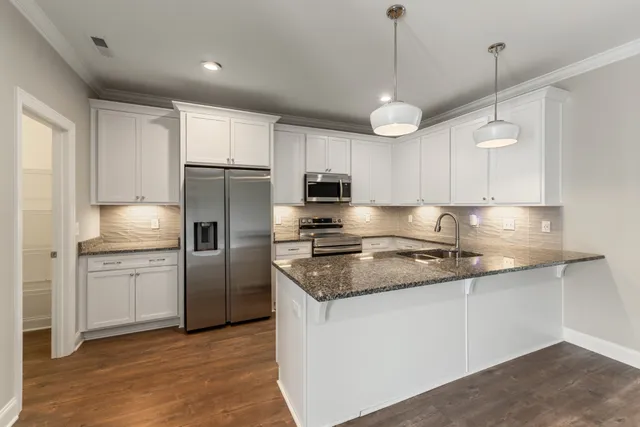 a kitchen with granite countertop white cabinets sink and stainless steel appliances