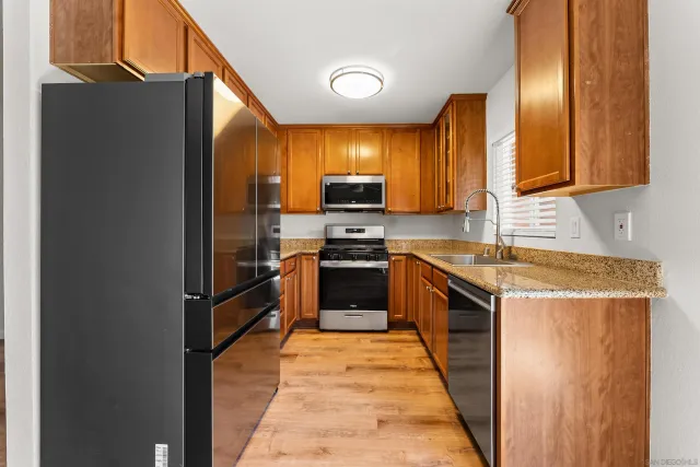 a kitchen with stainless steel appliances granite countertop a stove top oven a sink and a refrigerator