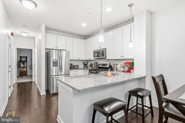 a kitchen with stainless steel appliances granite countertop a table chairs refrigerator and microwave