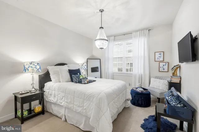 a bedroom with a bed a mirror and a flat tv screen on the dresser
