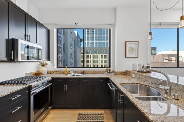 a kitchen with granite countertop a refrigerator and a stove top oven