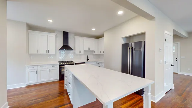a large kitchen with kitchen island a sink a stove a refrigerator and white cabinets