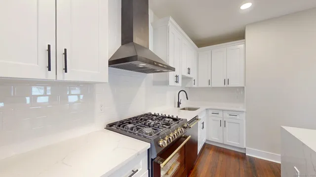 a kitchen with stainless steel appliances a stove and white cabinets