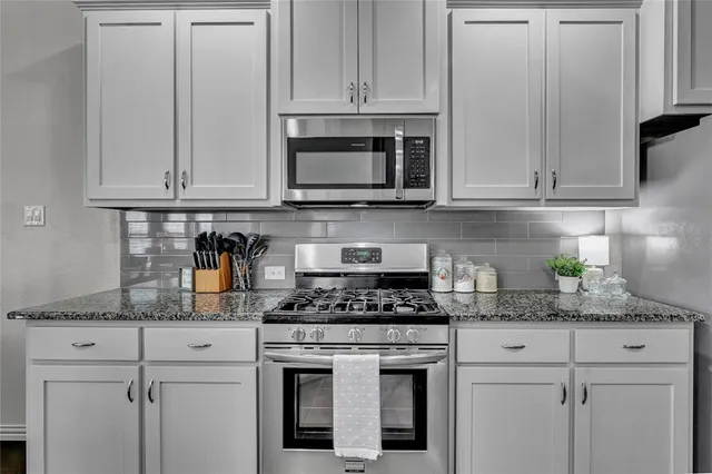 a kitchen with granite countertop white cabinets and stainless steel appliances