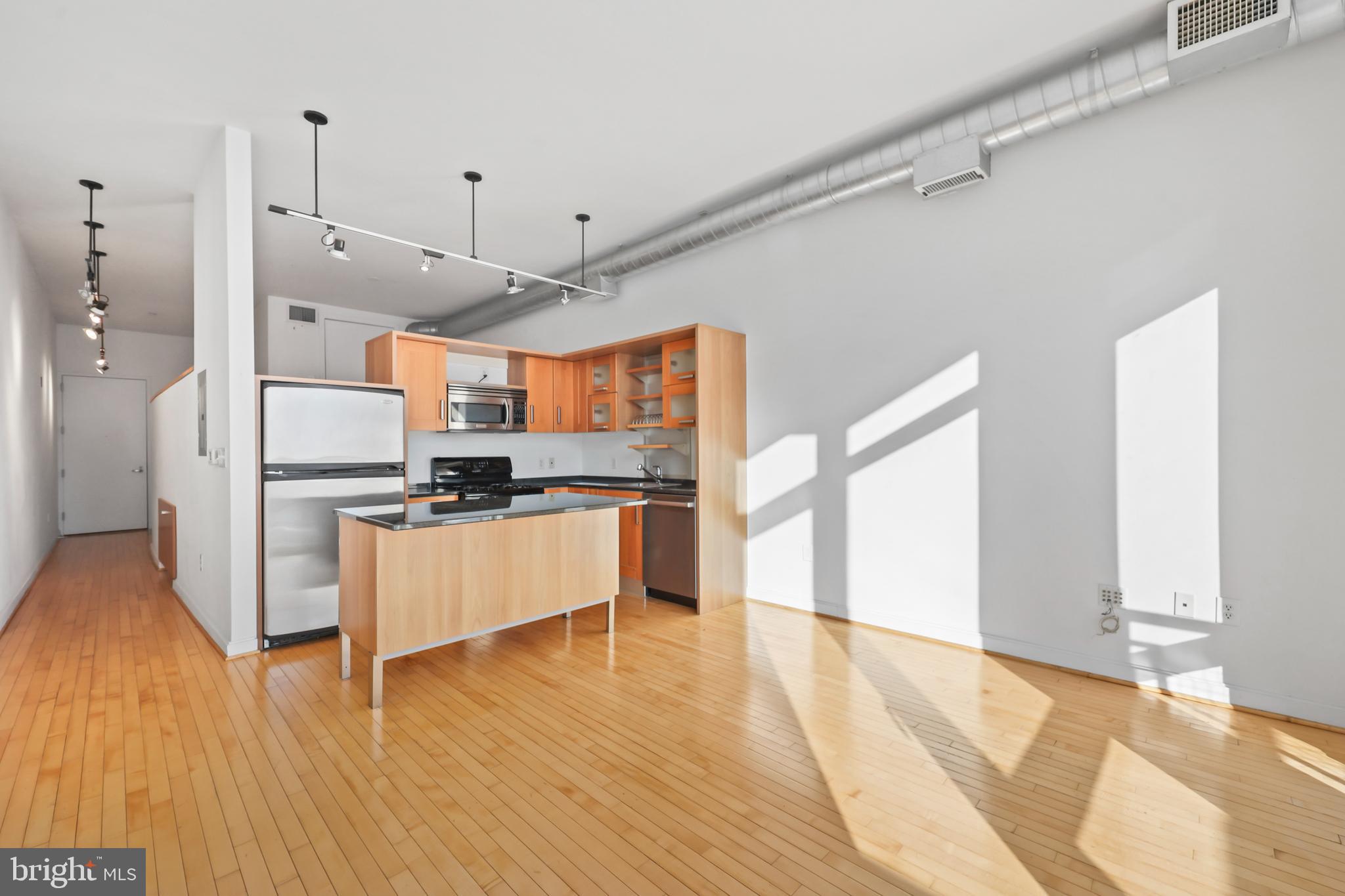1390 V Street Northwest, Unit 307 Washington, DC 20009 - Photo 6 of 34 a large kitchen with stainless steel appliances kitchen island granite countertop a refrigerator a stove a sink and white cabinets with wooden floor