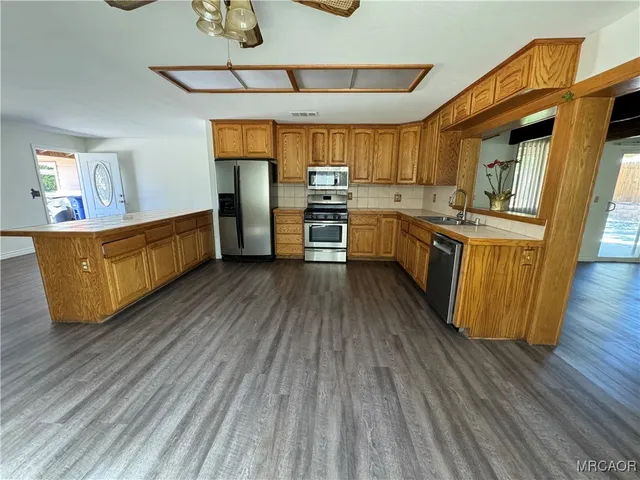 a kitchen with stainless steel appliances wooden floors stove top oven and cabinets