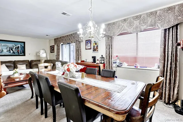 a view of a dining room with furniture a chandelier and large windows
