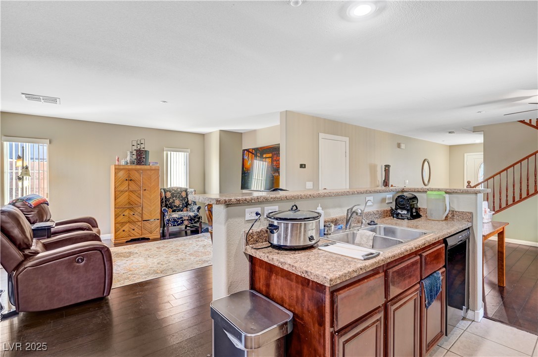 1168 Paradise River Road Henderson, NV 89002 - Photo 29 of 29 Kitchen with open floor plan, an island with sink, light wood finished floors, dishwasher, and brown cabinetry
