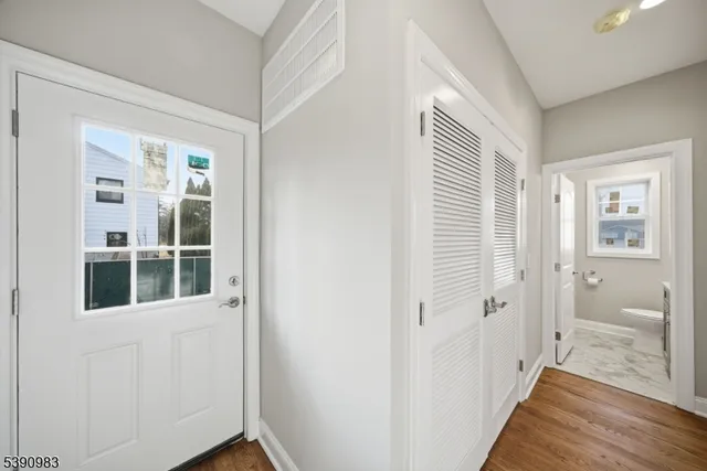 a view of a hallway with wooden floor and a bathroom