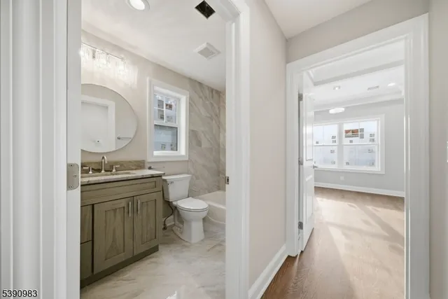 a bathroom with a granite countertop toilet a sink and a mirror