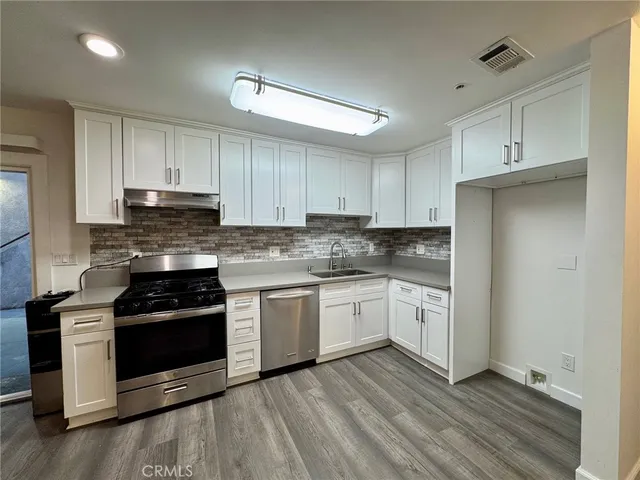 a kitchen with granite countertop white cabinets and stainless steel appliances