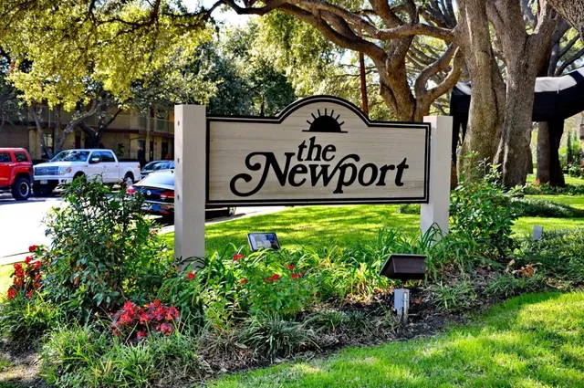 a view of sign board with flower and trees