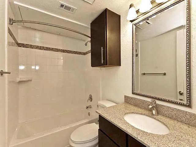 a bathroom with a granite countertop sink toilet and shower