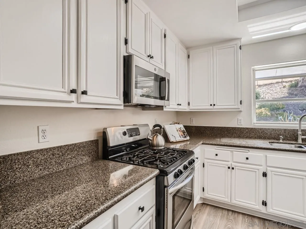 8515 Mesa Heights Road Santee, CA 92071 - Photo 9 of 28 a kitchen with granite countertop white cabinets and a stove top oven