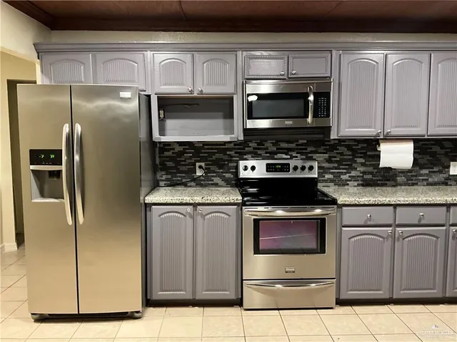 a kitchen with stainless steel appliances granite countertop a stove microwave and refrigerator