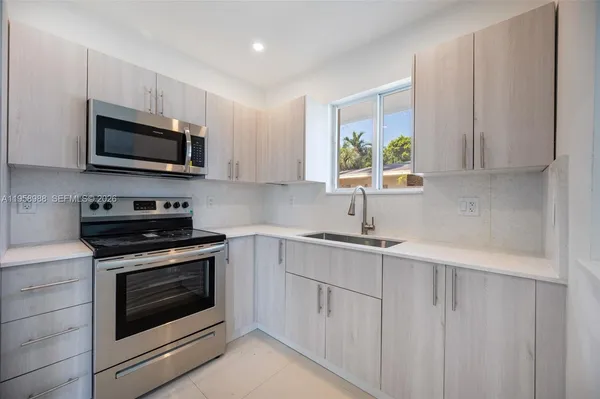 a kitchen with stainless steel appliances granite countertop white cabinets a sink and a stove