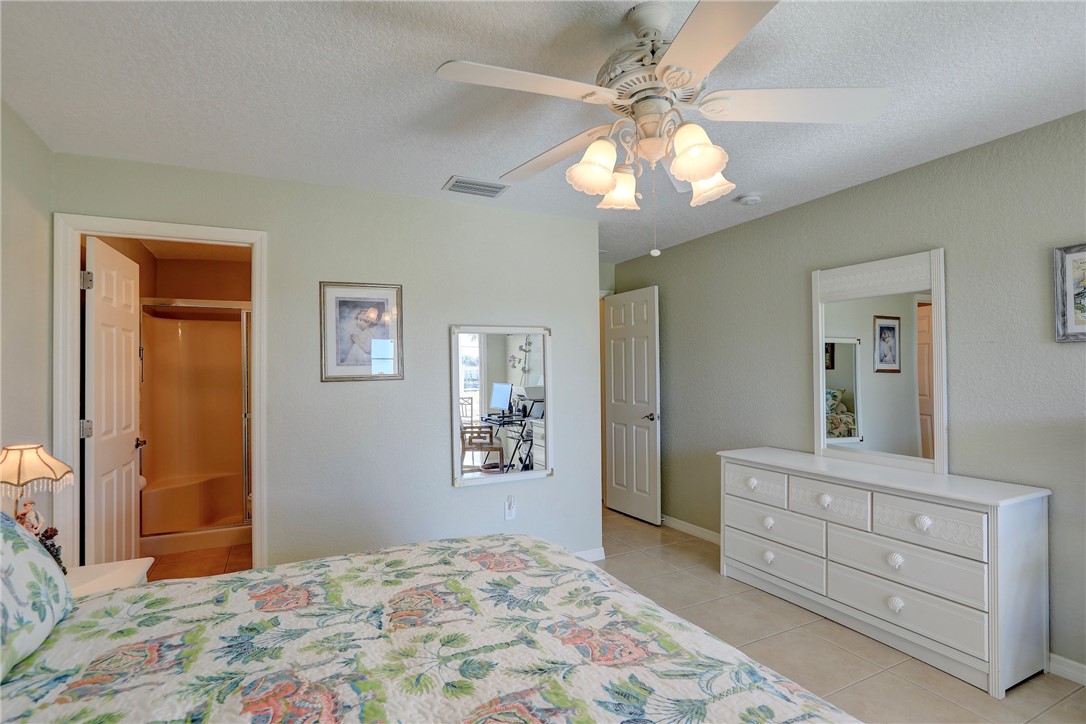 105 Spring Lake Court, Unit 207 Vero Beach, FL 32962 - Photo 14 of 34 a bedroom with a bed and a chandelier