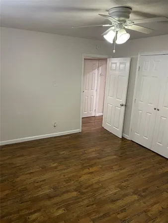 a view of an empty room with wooden floor and a ceiling fan