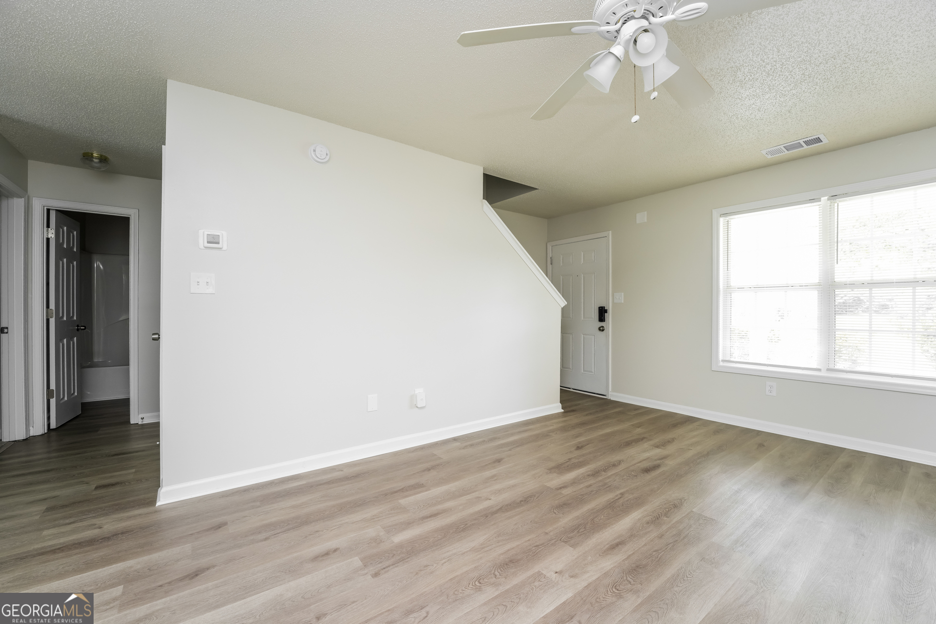 6930 Red Bone Way Lithonia, GA 30038 - Photo 3 of 17 an empty room with wooden floor fan and windows