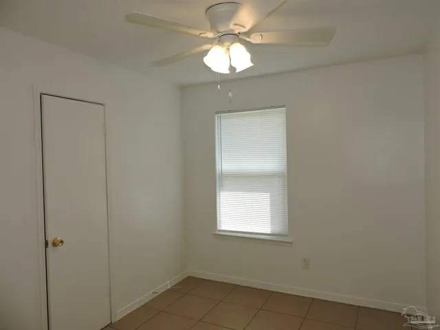 an empty room with a window and a chandelier fan