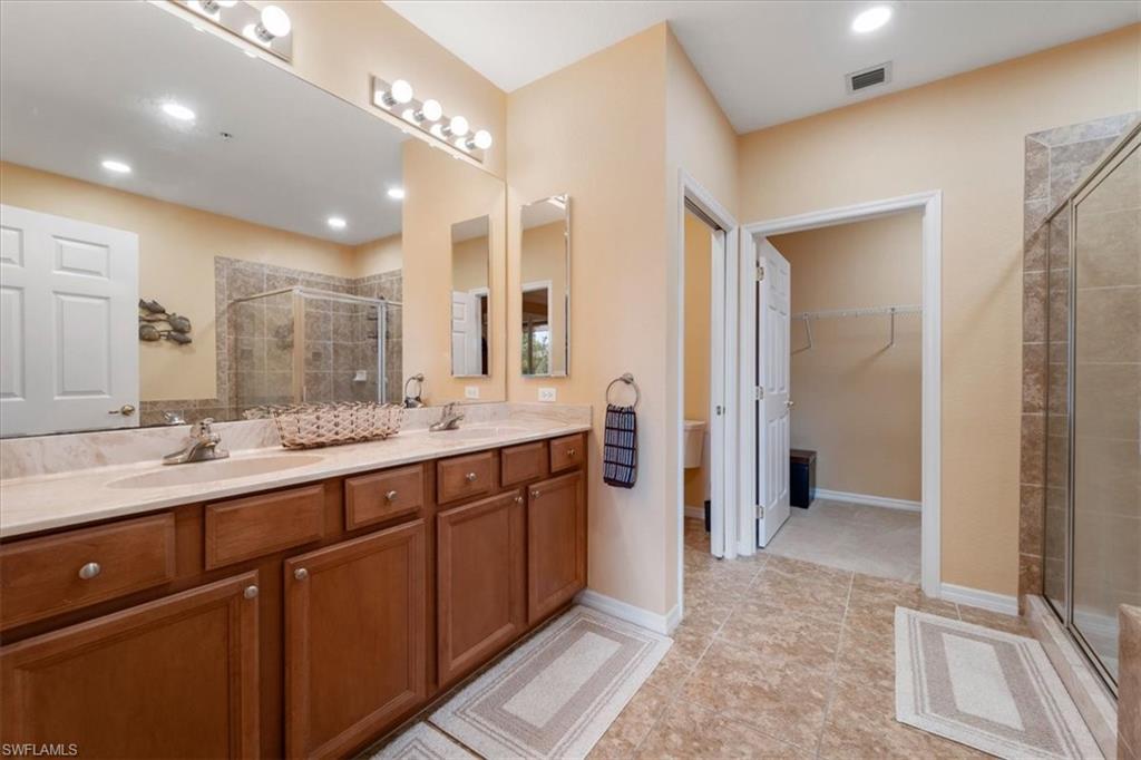 14981 Reflection Key Circle, Unit 322 Fort Myers, FL 33907 - Photo 11 of 35 a bathroom with a double vanity sink a mirror and a shower