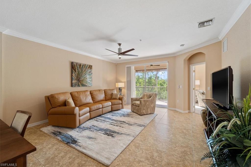 14981 Reflection Key Circle, Unit 322 Fort Myers, FL 33907 - Photo 3 of 35 Living room featuring arched walkways, crown molding, a ceiling fan, and light tile patterned floors